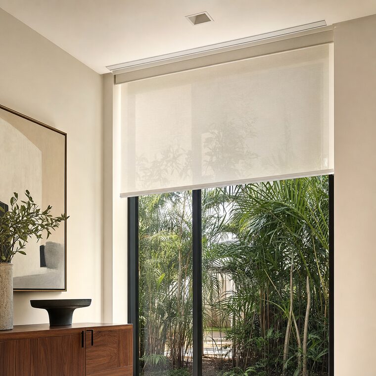 A close view of a slim cassette set flush into a ceiling pocket above a tall window, bone linen dropping from it in one plane with no cord, chain, or wand