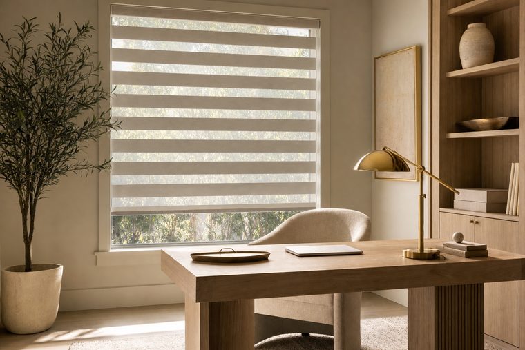 A home office with a white oak desk and a banded shade lowered over the window, the alternating sheer and solid bands clearly visible