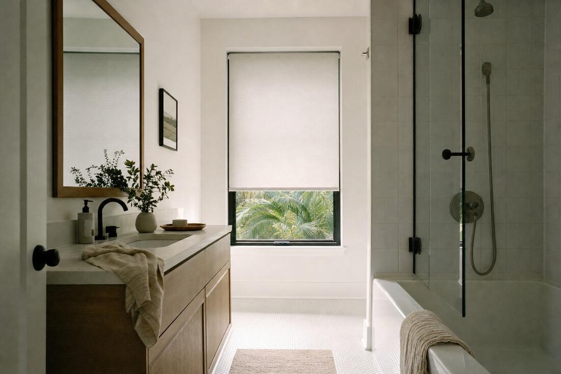 A white-tiled bathroom with an oak vanity, a pale roller shade lowered two thirds, flat and smooth with a straight bottom bar
