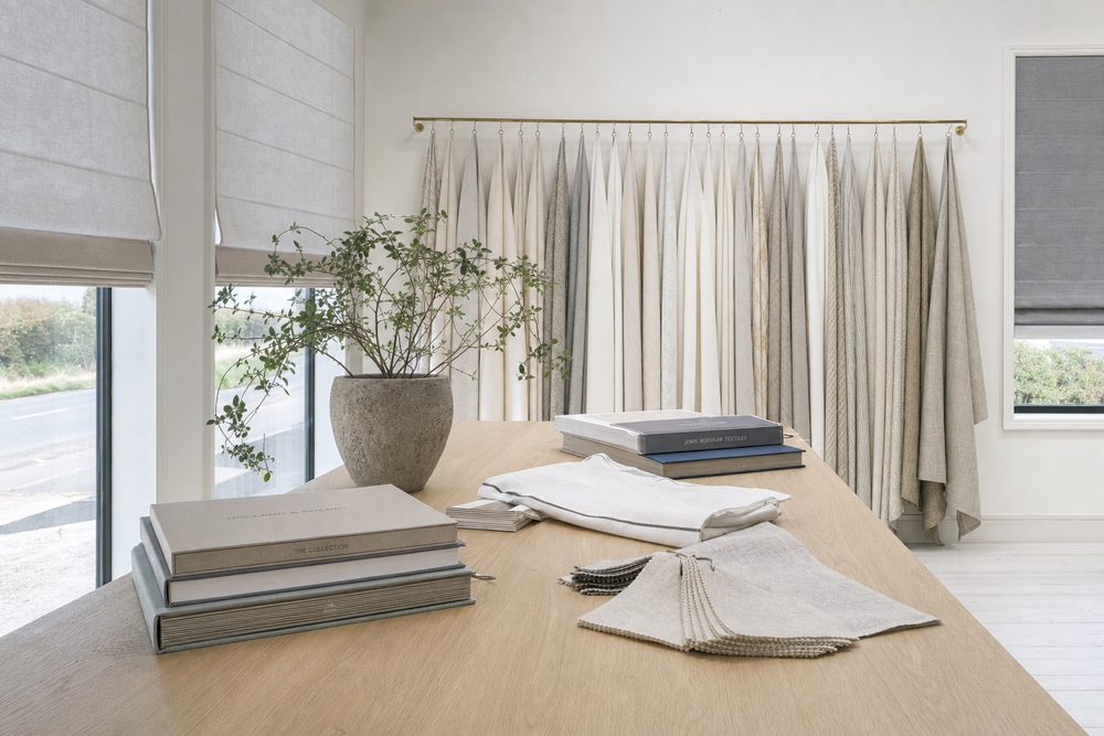 The Regency showroom: an oak table of fabric sample books beneath a wall of hanging swatches